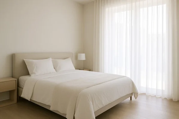 Dormitorio con cortinas visillo blancas y luz natural filtrada